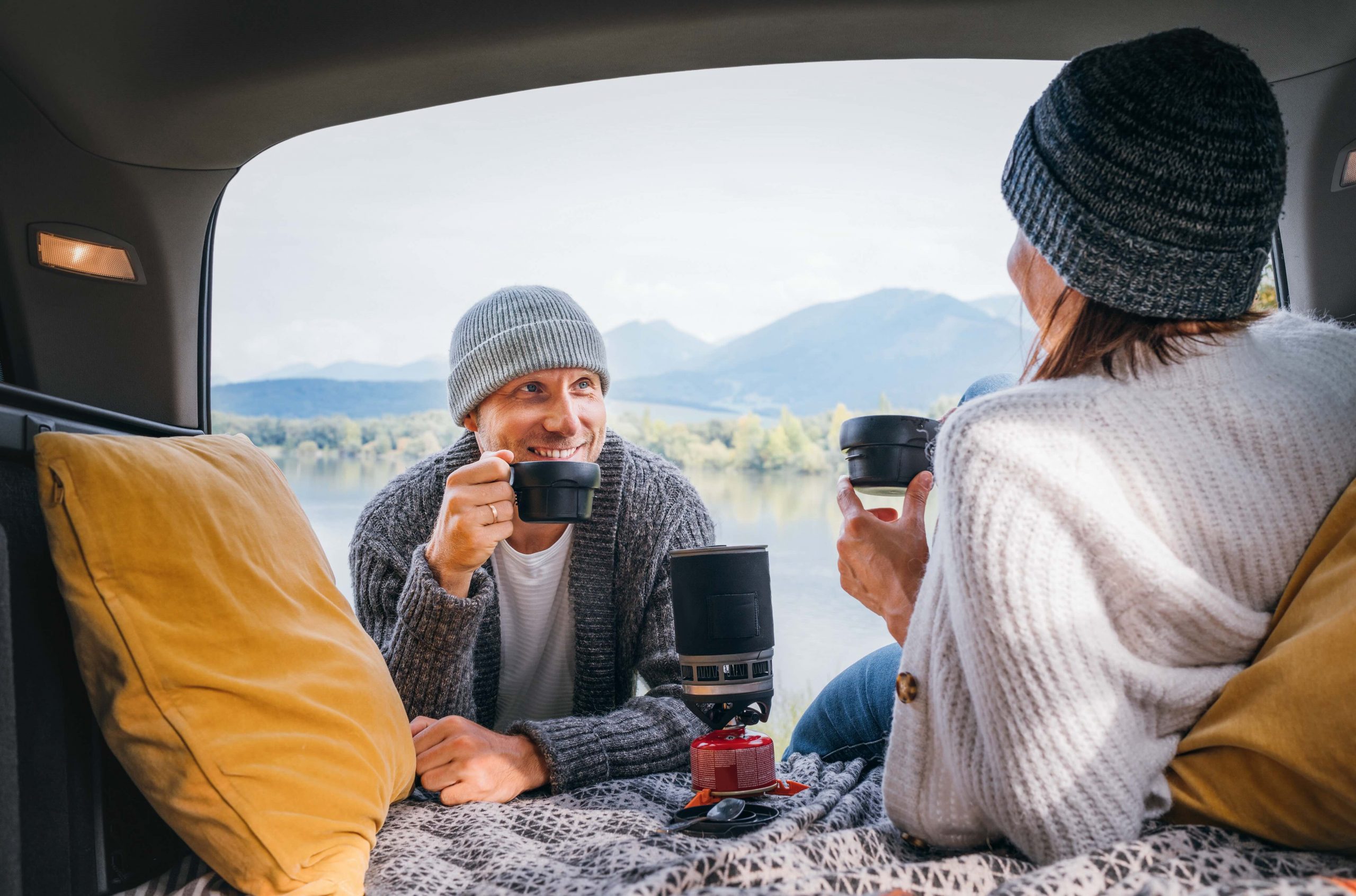 Happy couple talking and having a cup of coffee after camping in their van.